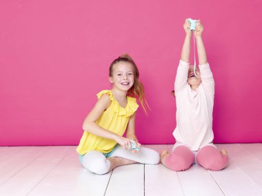 pembe arka plan önünde ev yapımı inceler ile oynarken eğlenen kız kardeşler 