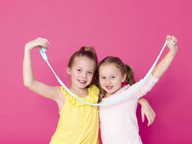 pembe arka plan önünde ev yapımı inceler ile oynarken eğlenen kız kardeşler 