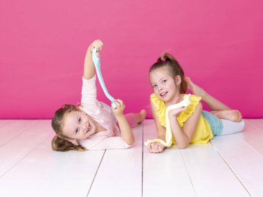 pembe arka plan önünde ev yapımı inceler ile oynarken eğlenen kız kardeşler 