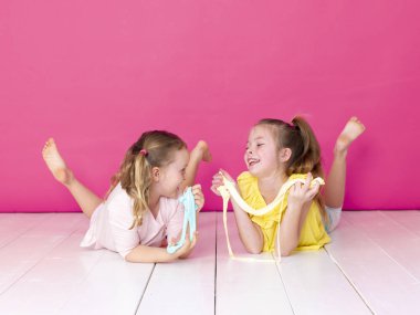 pembe arka plan önünde ev yapımı inceler ile oynarken eğlenen kız kardeşler 