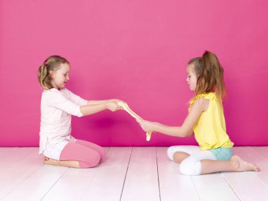pembe arka plan önünde ev yapımı inceler ile oynarken eğlenen kız kardeşler 