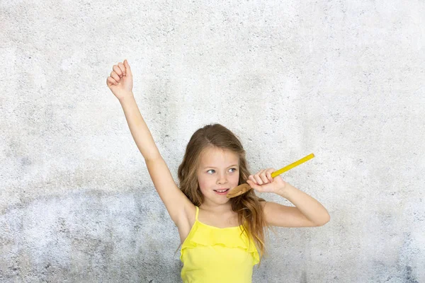 マイクとして調理スプーンを使用し 青い背景の前で歌うかなりクールな小さな女の子 — ストック写真