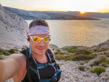 Hırvatistan 'ın Krk adasındaki Baska adasında spor giyim ve güneş gözlüklü izci selfie' si 