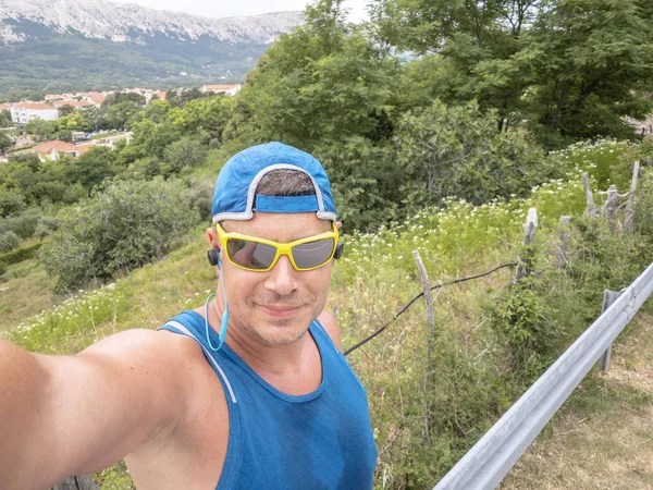 selfie of trail running man in sportswear and sunglasses in Baska on island Krk, Croatia