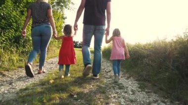Mutlu ebeveynler ve iki çocuk güneşli bir günde çayırda birlikte yürüyüp eğleniyorlar. 