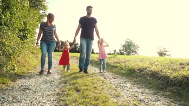 楽しい2人の子供を持つ幸せな両親は晴れた日に牧草地の近くを歩いて — ストック動画