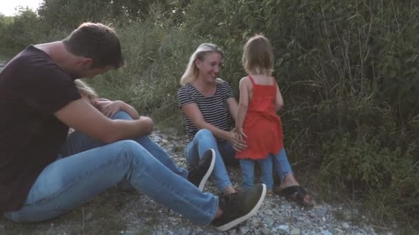 2人の子供を持つ両親は晴れた日に牧草地を歩き — ストック動画