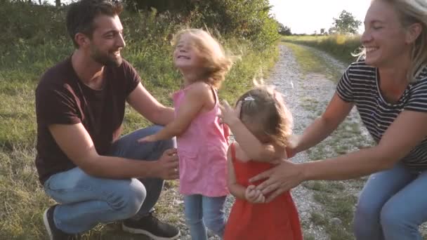 2人の子供を持つ両親は晴れた日に牧草地を歩き — ストック動画