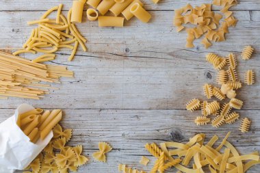 Farklı türde yumurta erişteleri ve ahşap arka planda sarı makarna.