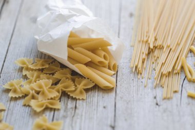 Farklı türde yumurta erişteleri ve ahşap arka planda sarı makarna.