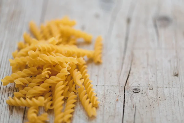 different kinds of egg noodles and yellow pasta on wooden background