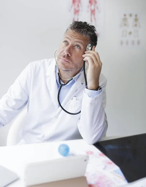 Portrait of a male doctor in his practice with a three-day beard and white coat