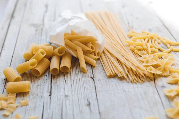 different kinds of egg noodles and yellow pasta on wooden background