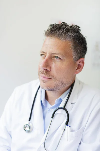 Portrait of a male doctor in his practice with a three-day beard and white coat