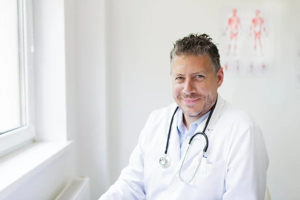 Portrait of a male doctor in his practice with a three-day beard and white coat