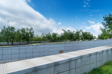 Mavi gökyüzünün ve beyaz bulutların altındaki park duvarı.