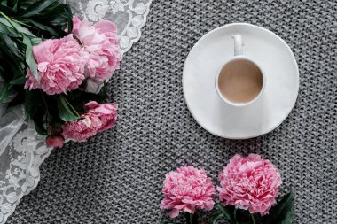 Bir fincan kahve ve gri arka plan üzerinde peonies