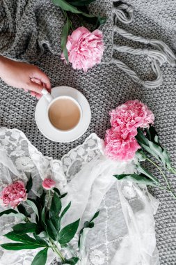 Bir fincan kahve ve gri arka plan üzerinde peonies
