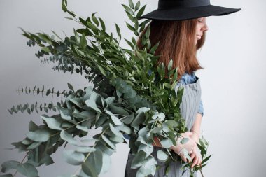 Çiçekçi bir buket yapar. İş süreci. Okaliptüs bir buket elinde tutan kadın