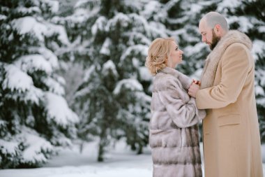 Gelin ve damat tarafından kar poz çam ağaçlarıyla kaplı