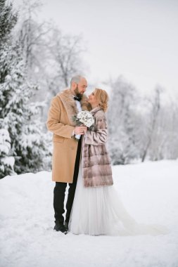 Gelin ve damat karlı sahnede poz romantik çekim