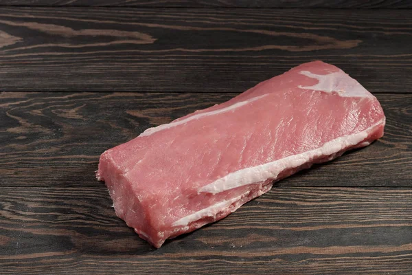 Whole boneless pork loin without fat. Pork tenderloin on a dark background