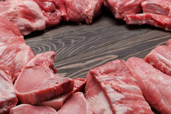 Různé syrové maso na dřevěné tmavé pozadí. Maketa — Stock fotografie