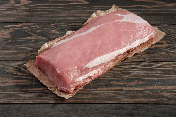 Whole boneless pork loin without fat. Pork tenderloin on paper on a dark background