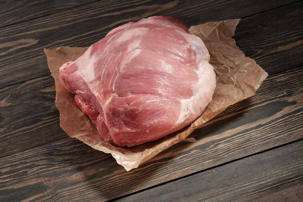 A piece raw pork shoulder. Pork tenderloin on paper on a dark background