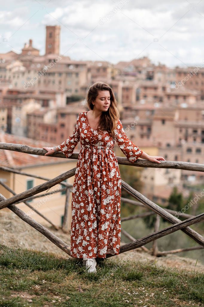 A beautiful girl in a long dress walking around the ancient  city of Siena 