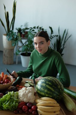genç vegan kadın ev iç sebzeler ile mutfak masasında telefon kullanarak