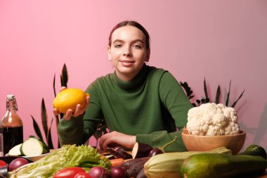 genç neşeli vejetaryen kız ev iç sebzeler ile masada limon tutan