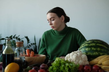 genç vegan kadın ev iç sebzeler ile mutfak masasında telefon kullanarak