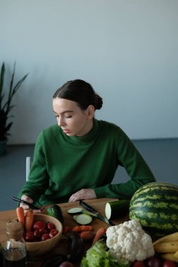 genç vegan kadın ev iç sebzeler ile mutfak masasında telefon kullanarak