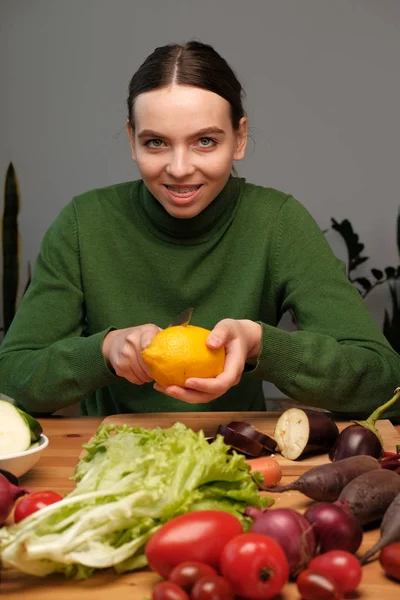 Joven Chica Vegetariana Alegre Sosteniendo Limón Mesa Con Verduras Interior — Foto de Stock