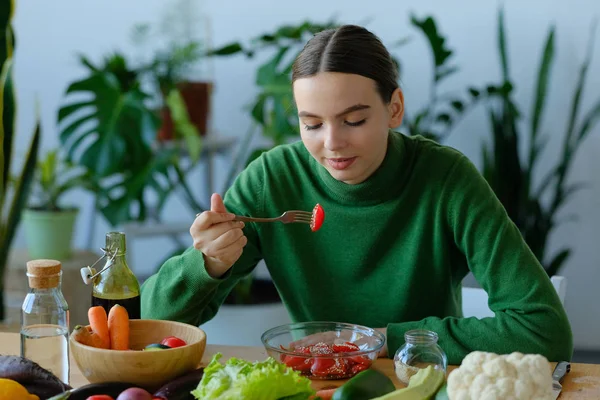 young vegan woman eating salad at kitchen in home interior