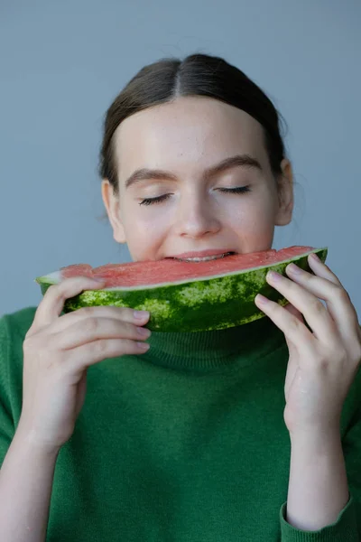 happy teen girl eating sweet watermelon slice at home