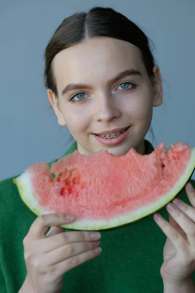 happy teen girl eating sweet watermelon slice at home
