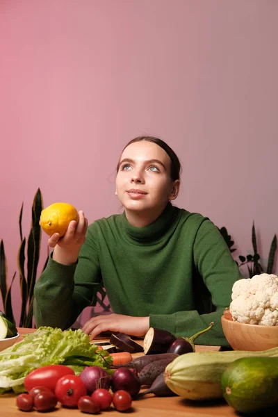 家庭のインテリアで食品テーブルでレモンを保持している若い女性 — ストック写真