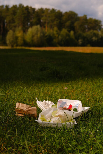 various plastic trash remains in countryside green meadow