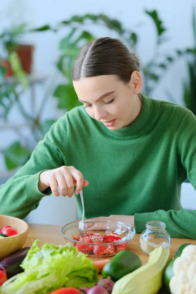 young vegetarian woman eating salad at kitchen in home interior
