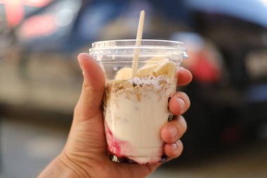 Kremsi tatlı ile plastik tek kullanımlık fincan tutan kişi el