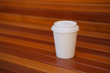 Ahşap arka planda beyaz plastik tek kullanımlık kahve fincanı