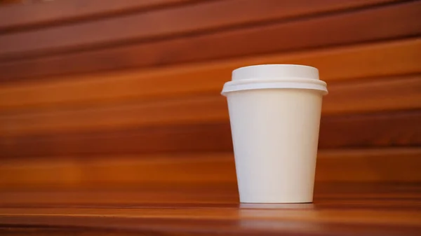 White plastic disposable coffee cup on wooden background