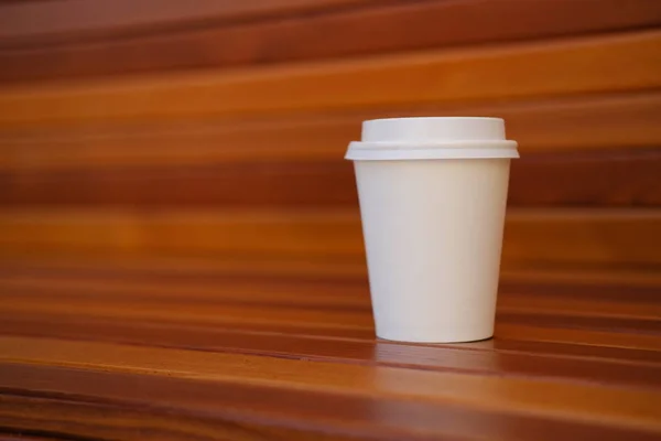 White plastic disposable coffee cup on wooden background