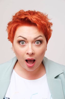 Sade arka planda heyecanlı kızıl saçlı kadının stüdyo portresi.