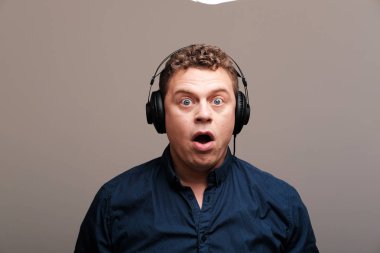 düz arka plan karşı kulaklık ile heyecanlı adam stüdyo portresi