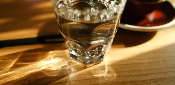 glass of fresh water with light pattern on wooden table
