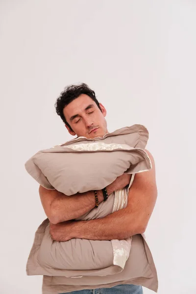 平凡な背景に枕を持つ眠い男のスタジオの肖像画 — ストック写真