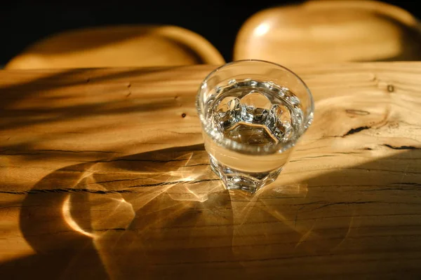 glass of fresh water with light pattern on wooden table